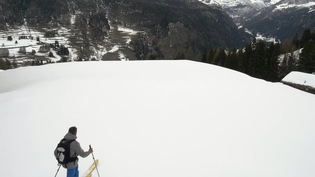 Winter aerial drone establisher over skier man skiing in snowy forest woods valley under iced mountains. mountain nature snow outdoors.Alps ski mountaineering activity.Forward flight.4k top view video