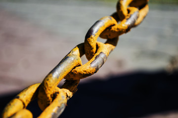 A large old yellow chain of rusty metal in the city. Urban.