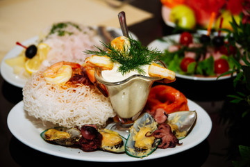 Fresh salad with smoked salmon, black olives, cherry tomatoes and edible flowers on wooden background.