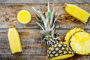 Freshly squeezed pineapple juice near fruit slices on wooden background top view