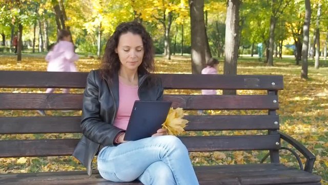 Family in the autumn park. A happy woman with a pannier resting in a bag with children.