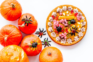 Gummy spiders crawls toward pie for halloween on white background top view