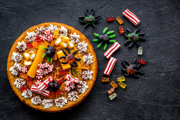 Fototapeta na wymiar Halloween sweets. Pumpkin pie and gummy figures on black background top view