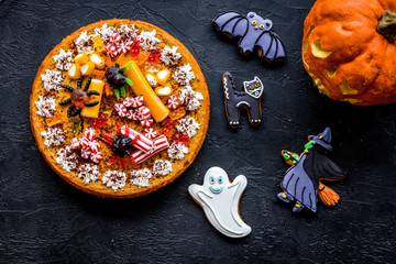 Halloween bakery and sweets. Pumpkin pie, gummy spiders, gingerbread cookies on black background...
