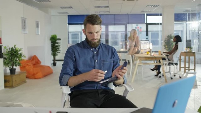 Bored businessman playing with stapler instead of doing his work in creative office.