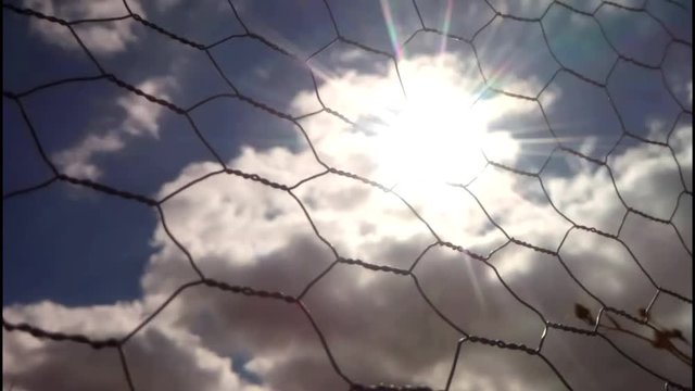 Time Lapse de Nubes y sol tras una malla de metal