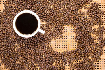 Flay lay style, Medium dark Roasted peaberry coffee beans with black coffee filled in coffee mug on bamboo handcraft background.