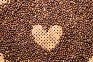 Flay lay style, Medium dark Roasted peaberry coffee beans with heart shape on bamboo handcraft background. coffee lover concept.