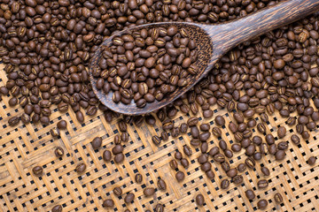 Flay lay style, Medium dark Roasted peaberry coffee beans in wooden big spoon on bamboo handcraft background.