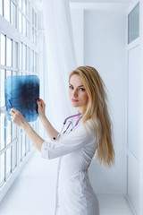 Portrait of young woman doctor with stethoscope and x-ray