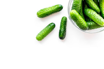 Fresh cucumbers in bowl on white background top view copyspace