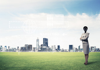 Camera headed woman standing on green grass against modern citys