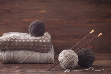 Tweed wool yarn with wooden knitting needles. Knitted sweaters.