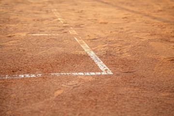 Ground on tennis court with white lines in daylight.  