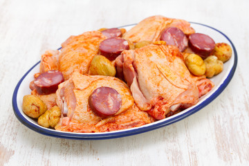 raw marinated chicken with smoked sausages on dish
