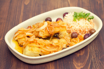 fried codfish with boiled rice and olive oil on dish