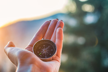 Girl holding a compas in a hand on the carpathian mountains background during the sunset