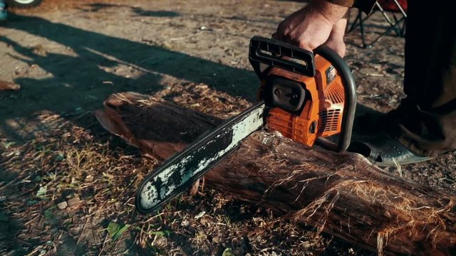 Chainsaw sawing dry wood lying on ground. Man cutting wood with chainsaw