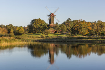 Fototapeta premium Colorful windmill standing on the shore of the lake