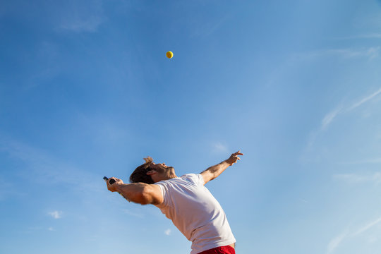 Professional tennis player throwing ball in the air before hitting it. 