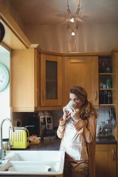 Thoughtful woman having coffee in kitchen