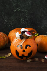 Terrible sweets for Halloween in decorative pumpkin on a dark background