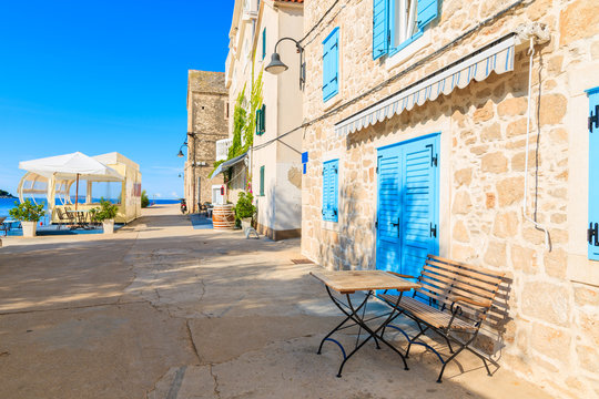 Small table in front of coastal restaurant with blue windows old town of Primosten, Dalmatia, Croatia