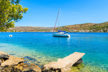 Sailboat on sea and beach with turquoise crystal clear sea water in Rogoznica town, Dalmatia, Croatia