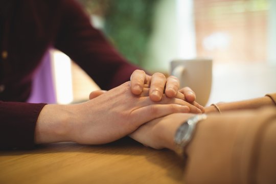 Couple holding hands while relaxing at home