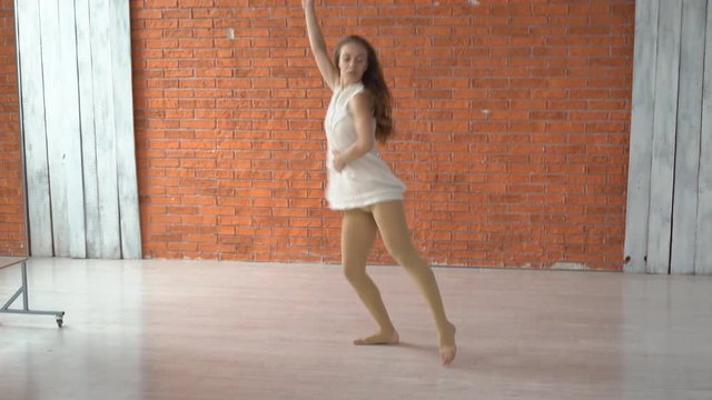 sad girl is preparing to perform in the theater. the actor rehearses the dance in the dance hall. the woman wore a white free dress. dramatic scene with a dance on the floor. professional dancer
