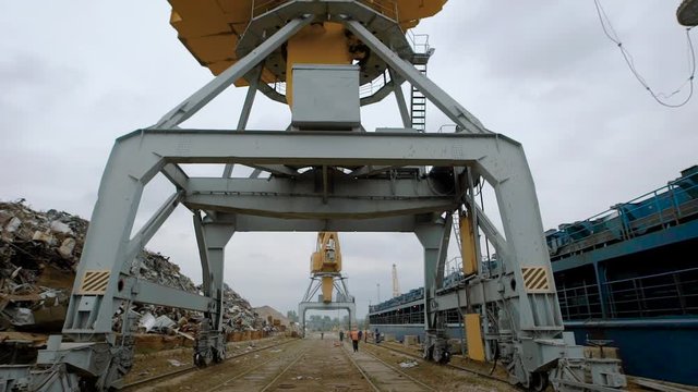 huge industrial crane are standing in a wrecking yard of a scrap metal processing plant in cloudy weather in summer day