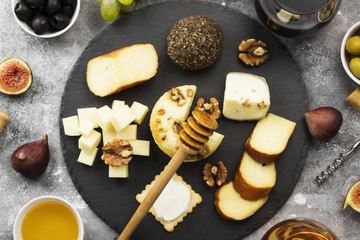 Snacks with wine - various types of cheeses, figs, nuts, honey, grapes on a gray background. Top view. Food background