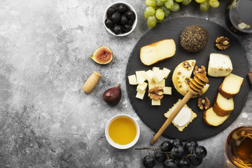 Fototapeta na wymiar Snacks with wine - various types of cheeses, figs, nuts, honey, grapes on a gray background. Top view, copy space. Food background