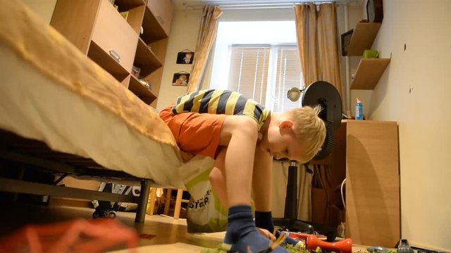 A boy 8 years old removes toys after play in an ordinary home environment
