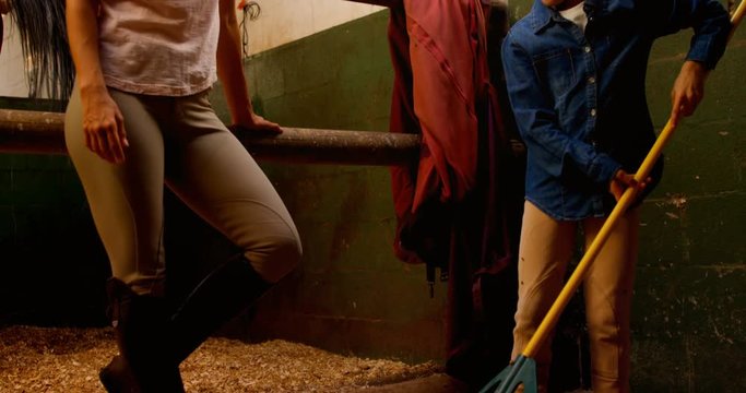 Mother and daughter giving high five to each other in stable 
