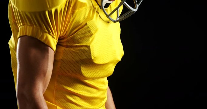 American football player standing against black background 