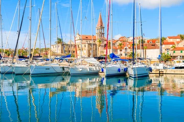 Poster Reflection of sailing boats anchoring in beautiful Milna port with church tower in background, Brac island, Croatia © pkazmierczak