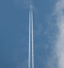 Airplane flying at high altitude leaving its white wake over blue sky