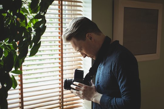 Man holding vintage camera near window