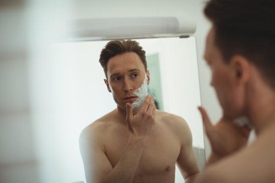 Man applying shaving foam in bathroom