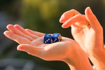 Dice 1 1 in the female hand, sunset background. Gambling devices.