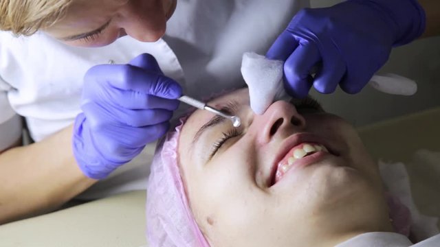 beautician squeezing pimple blackheads from nose with pimple popper tool