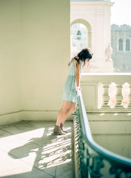 young woman gazing down from top of stair case