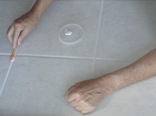 Painting and Sealing Tile Grout Lines. Male homeowner uses toothbrush and grout color/sealer to...