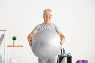 Senior man with fitball in physiotherapeutic center © Africa Studio
