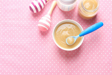 Ceramic bowl with baby food on color background