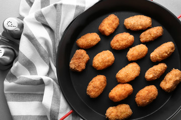 Frying pan with salmon croquettes on table