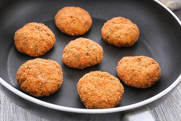 Delicious salmon patties on frying pan, closeup