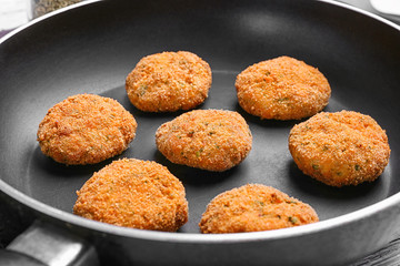 Delicious salmon patties on frying pan, closeup