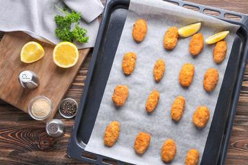 Fototapeta na wymiar Baking tray with delicious salmon croquettes on table